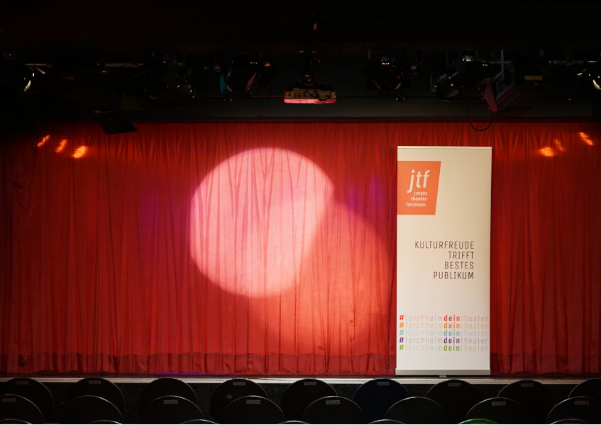 Bühne mit rotem Bühnenvorhang und Schild "Junges Theater"