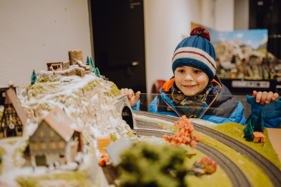 ein Junge mit Jacke und Mütze bestaunt die Modelleisenbahn im Pfalzmuseum