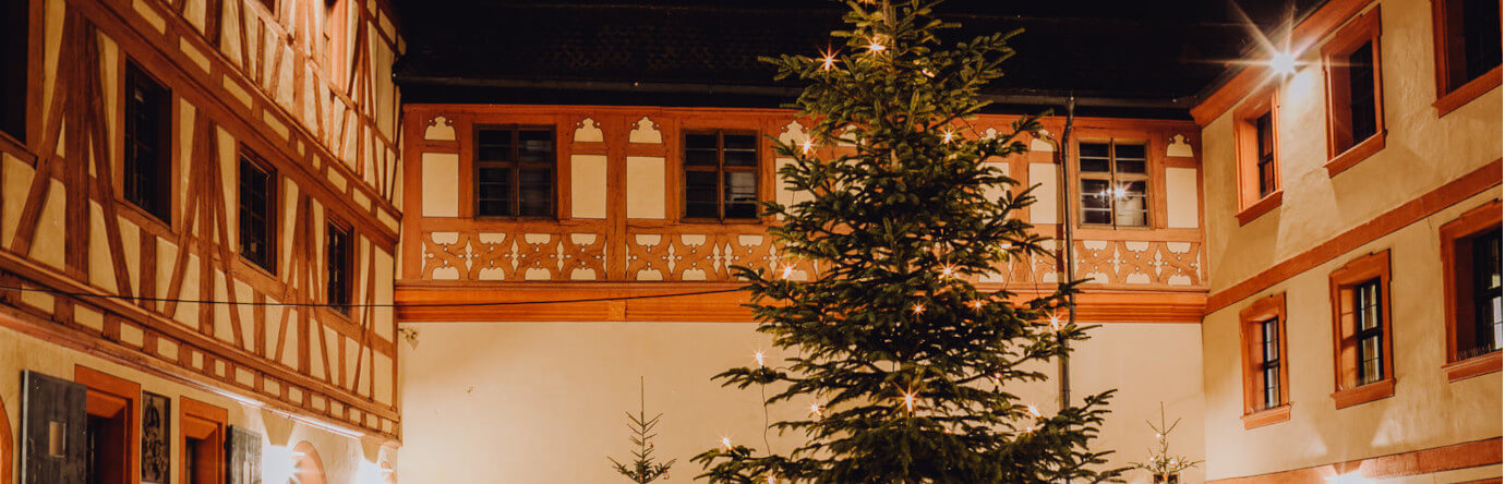 Fachwerkfassade im Innenhof der Kaiserpfalz Forchheim bei Nacht und Tannenbaum mit Lichterkette